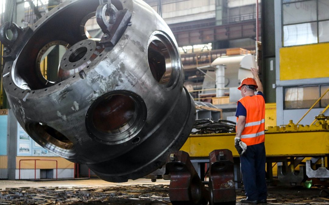 seorang pekerja sedang mengoperasikan alat untuk mengangkat spare part yang besar