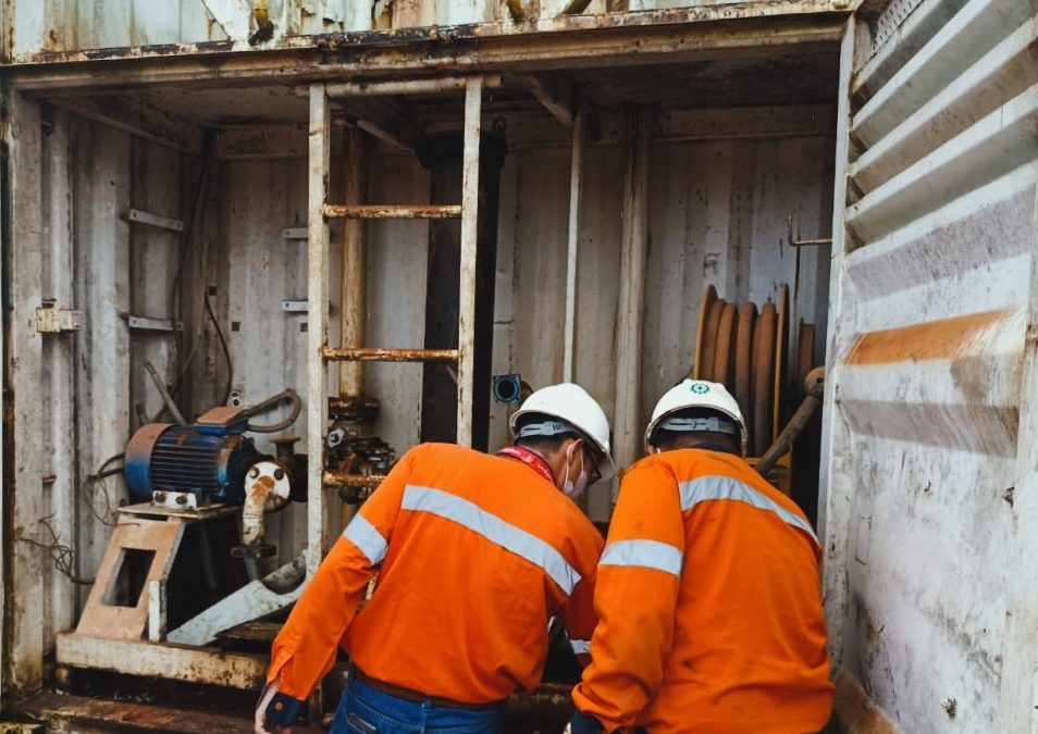 2 orang pekerja sedang mengecek sebuah bagian pada trailer/truk