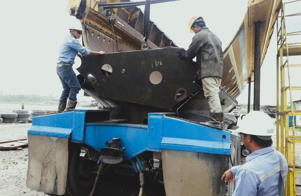 pekerja sedang melakukan perawatan pada truk/trailer tambang