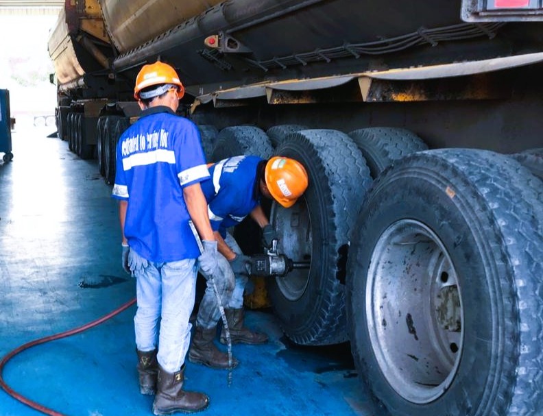 pekerja sedang melakukan perawatan pada ban truk/trailer tambang
