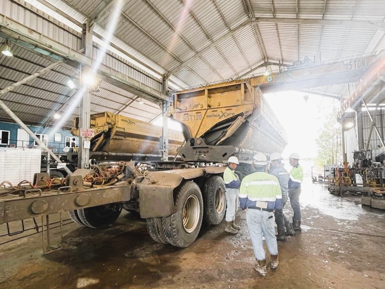 Pekerja sedang melakukan cek terhadap truk/trailer tambang di area service