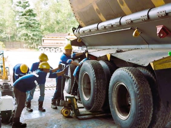 pekerja TDU sedang melakukan perawatan penggantian spare part pada truk/trailer tambang
