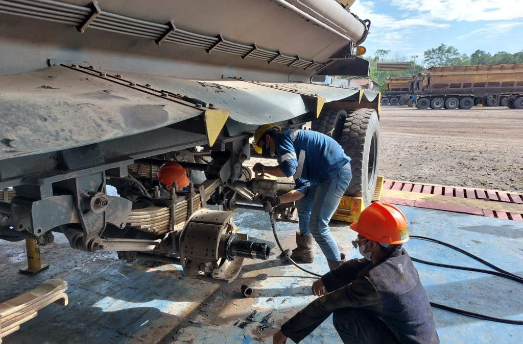 pekerja sedang melakukan perawatan 'pengencangan rubber torqued' pada truk/trailer tambang
