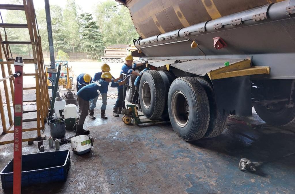 pekerja sedang mengganti ban truk tambang