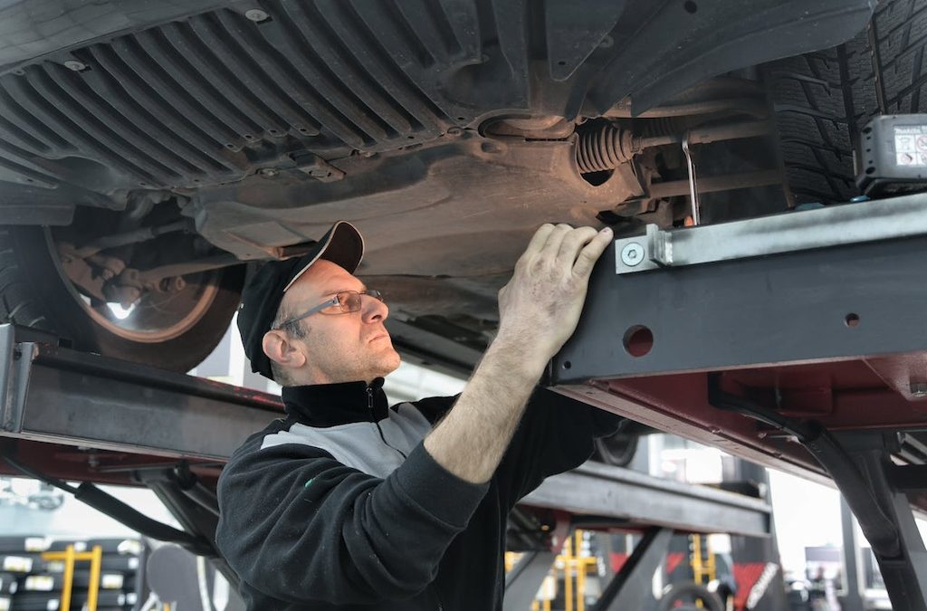 mechanic sedang melihat mesin bawah kendaraan