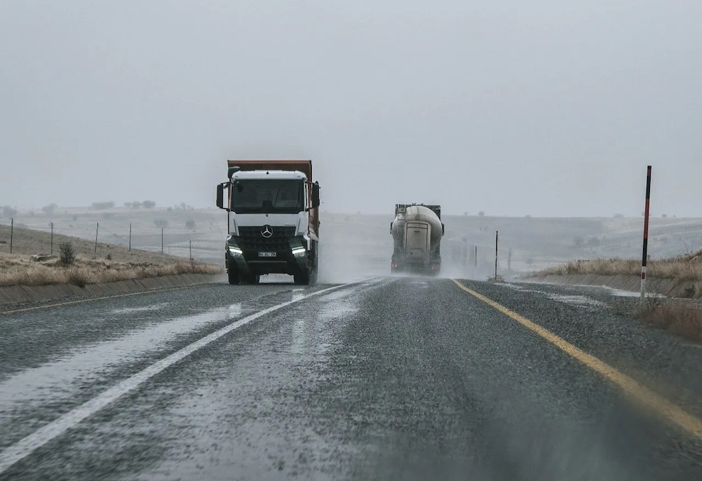 Trucks on rainy highway under overcast sky